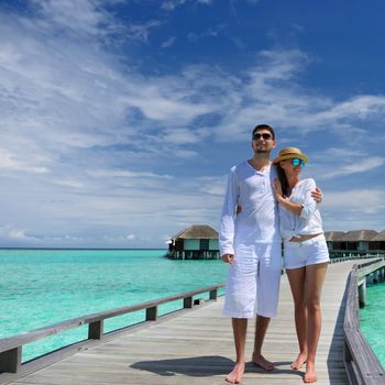 Couple on a tropical beach jetty at Maldives