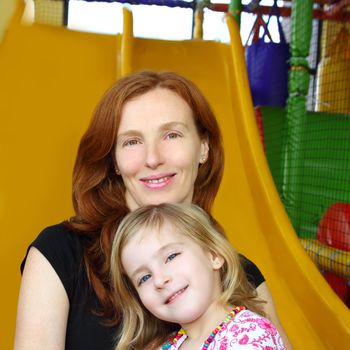 daughter and mother together in playground yellow slide