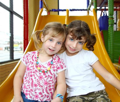 girls sister friends on playground yellow play slide smiling portrait