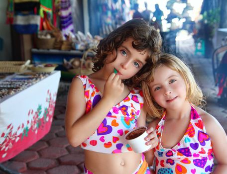 beautiful sisters little girls eating chocolate ice cream in mexican market