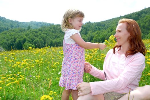 Daughter and mother playing in spring flowers meadow outdoor