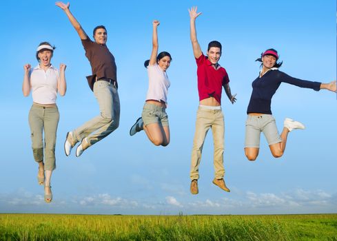 Jumping young people happy group in meadow blue sky outdoor