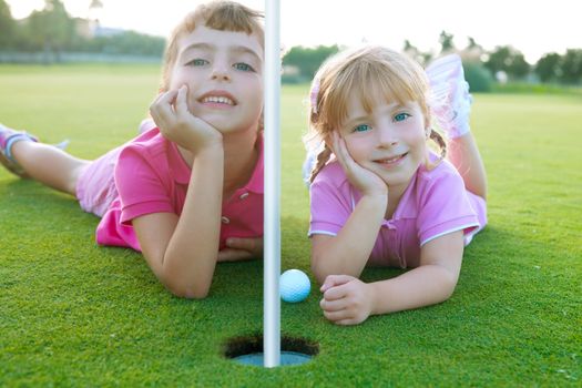 Golf two sister girls relaxed lying near green hole with ball