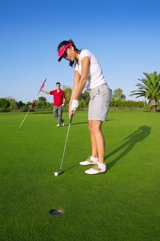 golf woman player green putting hole golf ball a man holding flag