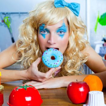 Blonde funny girl on kitchen eating blue donut with fashion makeup