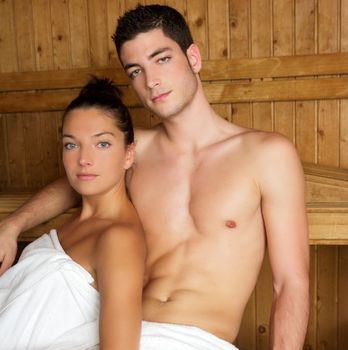 Sauna spa therapy young couple in warm wooden room white towel