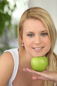 Blond girl resting chin on green apple