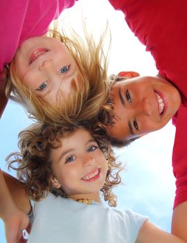 Below view of happy three children embracing hug each other smiling camera