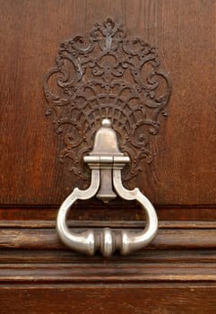 An Ornamental Door Knocker And Handle On An Old Wooden Door