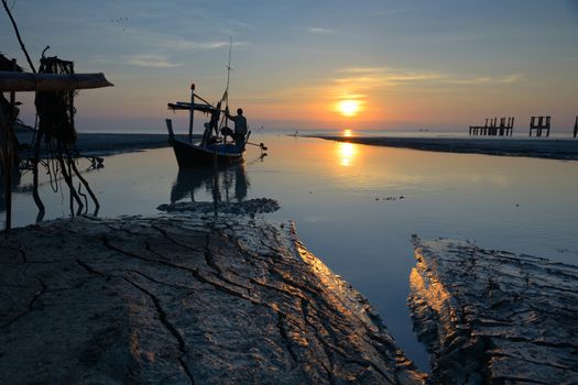 Fisherman is standing on fishing boat with sunrise background at thailand