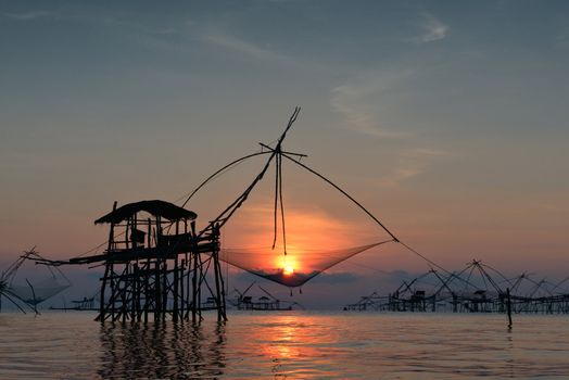 silhouette traditional fishing method using a bamboo square dip net with sunrise background in Patthalung, Thailand