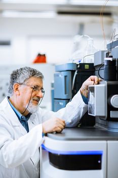 Senior male researcher carrying out scientific research in a lab (shallow DOF; color toned image)