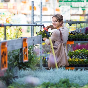 Young woman buying flowers at a garden center (color toned image; shallow DOF)