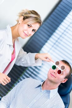 Optometry concept - handsome young man having his eyes examined by an eye doctor