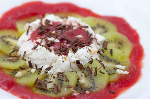 Dessert with cottage cheese served with chocolate shaving, grated nuts and sliced kiwi and strawberry jam