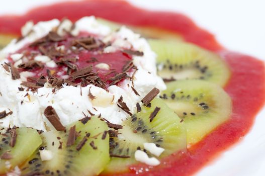 Dessert with cottage cheese served with chocolate shaving, grated nuts and sliced kiwi and strawberry jam