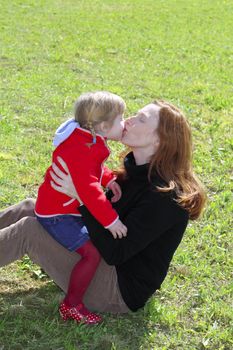 mother and daugther kissing mouth lips hug in winter meadow grass