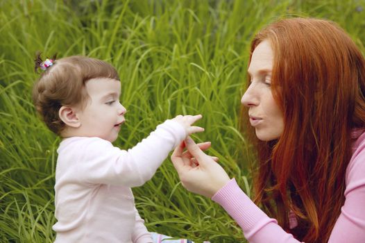 baby and redhead mother outdoor grass playing park together