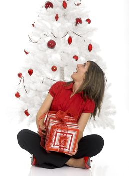 Beautiful happy woman near a white Christmas tree holding Christmas presents