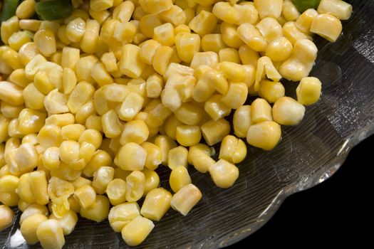 Precooked corn on a glass dish on a black background