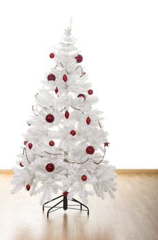 Christmas white tree with red ornaments in a house