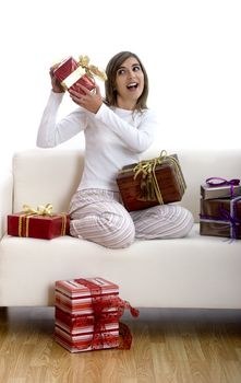 Woman in pajama seated on a sofa holding a Christmas gift