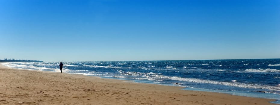 Beach with running man in the early morning light