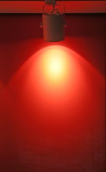 A spotlight is pointed towards a bright red wall.