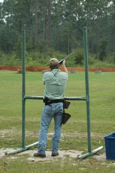 A skeet shooter takes aim at the clay just released.