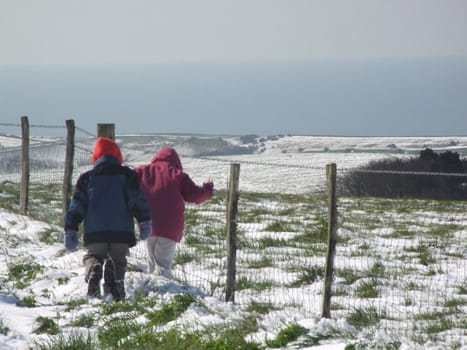 shot of two children on a farm playing in the snow