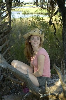 A young woman in a straw hat in the woods on the beach.