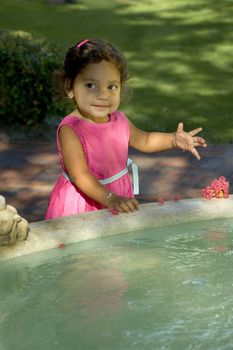A little Indian girl plays in a fountain.