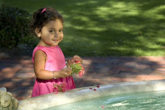 A little Indian girl plays in a fountain.