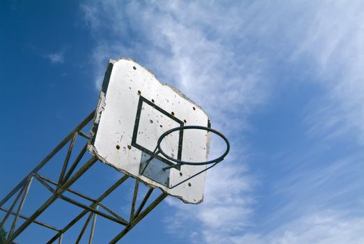 old grungy basketball hoop against blue sky