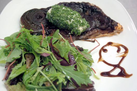 Red Onion Tart with green salad leaves and balsamico decoration