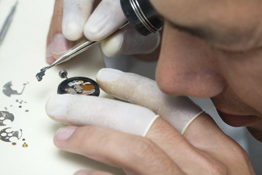 A watchmaker or repair man in action, viewing very closely a swiss watch.