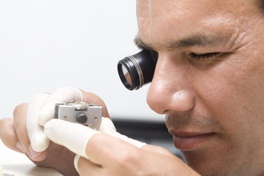 A watchmaker or repair man in action, viewing very closely a swiss watch.