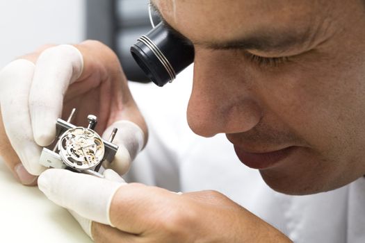 A watchmaker or repair man in action, viewing very closely a swiss watch.