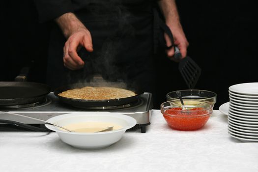 The cook fries pancakes with caviar