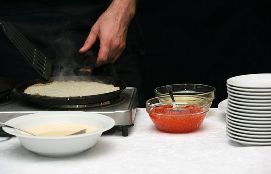 The cook fries pancakes with caviar