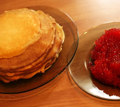Pile of pancakes and caviar on transparent plates