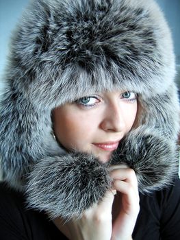 Beautiful girl in fur cap and blue eyes