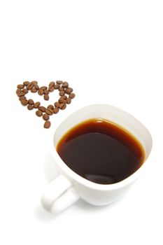 cup of coffe and coffee beans in heart shape on white