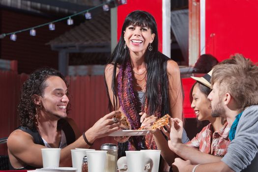 Joyful group of friends sharing pizza slices outdoors