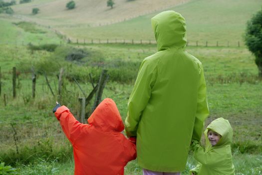 Green meadow with plastic waterproof coat colorful family in front
