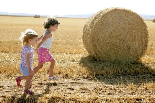 Girls playing with the round wheat dried bales outdoor summer