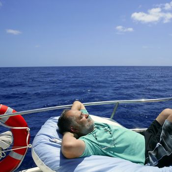 Sailor senior man having a rest on summer boat over blue ocean