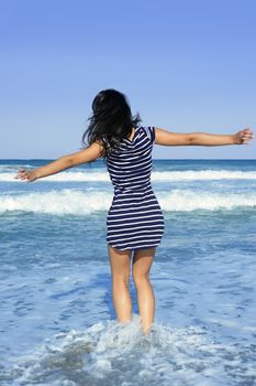 Beautiful summer indian brunette girl jumping on the blue beach