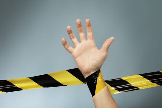Hand tangled in yellow and black barrier tape.