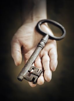 Man holding big antique key in his hand. Very short depth-of-field.